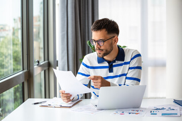 Business professionals. Business man analyzing data using computer while spending time in the office. Young grinning professional man in office. Graphs and charts