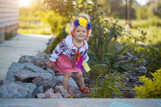 cheerful little girl in national Ukrainian clothes in a sunny summer garden