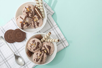 Chocolate homemade ice cream decorated with nuts, chocolate chips, wafer rolls, in white bowl. Summer cooling desserts
