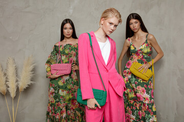 Three fashion models. Asians in identical looks, green dress with floral pattern, handbag, clutch....