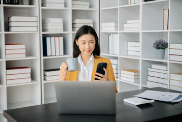 Confident Asian woman with a smile standing holding notepad and tablet at the office..