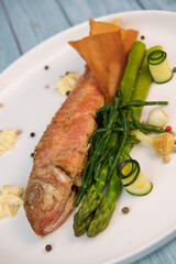 Plate of fried small fish red mullet with green asparagus. High quality photo