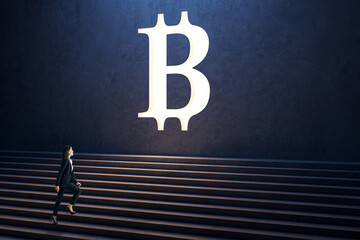 Side view of thoughtful young businesswoman climbing stairs to white bitcoin sign on concrete wall background. Cryptocurrency and success concept.