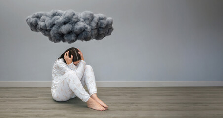 Unrecognizable woman with mental disorder and suicidal thoughts holding her head with hands sitting under a dark storm cloud on her room. Negative emotions and bad feelings concept.