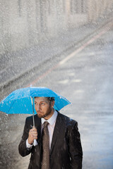 Businessman under tiny umbrella in rainy street