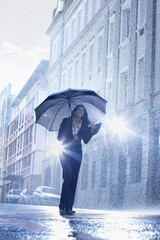 Businesswoman standing under umbrella in rainy street