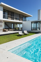 Lounge chairs and swimming pool outside modern house