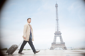 Businessman pulling suitcase near Eiffel Tower, Paris, France