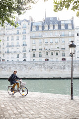 Obraz premium Man riding bicycle along Seine River, Paris, France