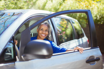 Portrait of confident senior woman getting out of car