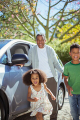 Enthusiastic grandfather and grandchildren running outside car