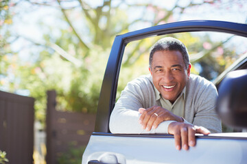 Portrait of confident senior man leaning against car door