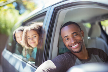 Portrait of happy family leaning out car windows