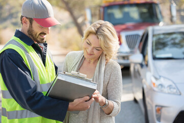 Roadside mechanic and woman reviewing paperwork