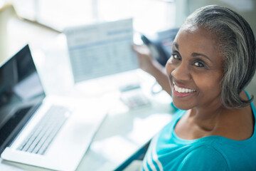 Portrait of smiling woman paying bills at laptop