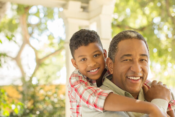 Portrait of smiling grandfather and grandson hugging outdoors