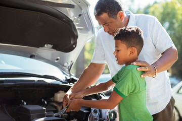 Grandfather and grandson repairing car engine