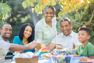 Portrait of happy multi-generation family eating lunch at patio table