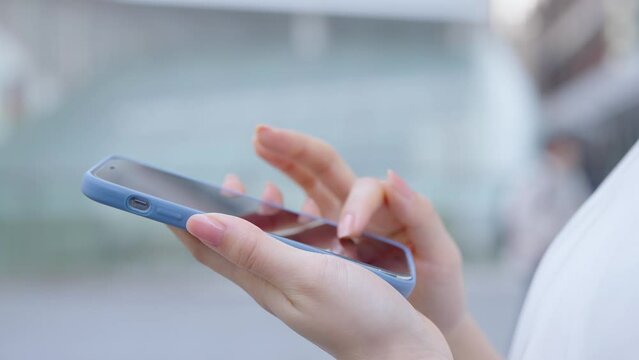 街角でスマートフォンを使う女性の手元
