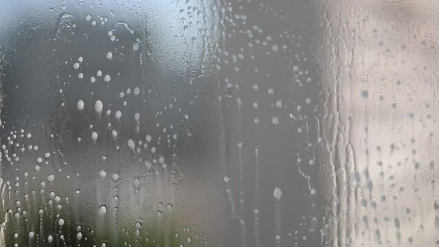 Liquid for washing glasses. Washing windows. The person splashes glass cleaner on the window and wipes the window with a microfiber cloth. Horizontal video.