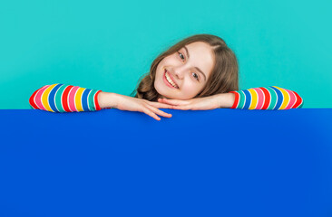 positive child behind blank blue paper with copy space for advertisement