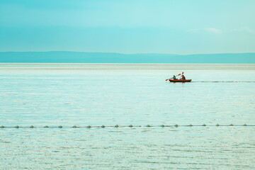 Two people rowing a inflatable dinghy boat at Kvarner gulf of Adriatic sea in summer morning. Active vacation lifestyle concept.