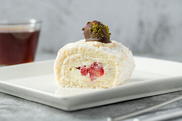 Strawberry roll cake with tea next to it on stone table