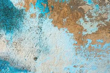 Blue paint peeling off the old concrete wall of a worn house as background