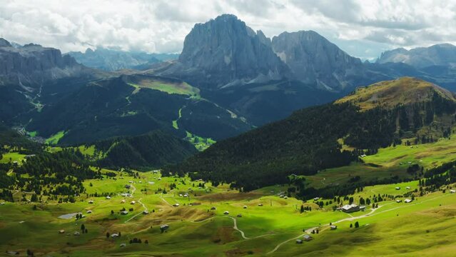 At the top edge of the Seceda ridgeline, a woman tourist captures stunning photos of the scenic landscapes, while embracing the untamed beauty of the wild nature in the Italian Alps from an aerial