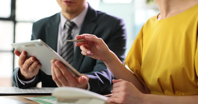 Business people talking using a digital tablet sitting at office table. Team working looking at touchpad screen of technical device