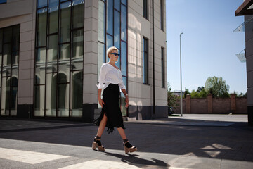 Confidence and Beautiful blonde woman with stylish short haircut walks city streets in fashionable...