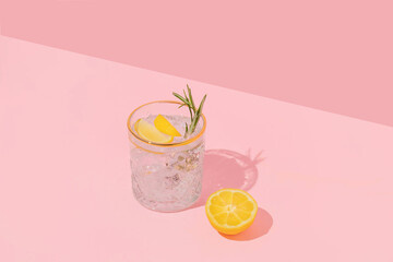 Summer creative layout with coctail glass and lemon half on pink background. 80s or 90s retro aesthetic idea. Minimal summer coctail idea.