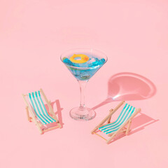 Summer creative layout with martini coctail glass with duck swim ring and beach chairs on pink background. 80s or 90s retro aesthetic idea. Minimal summer coctail idea.