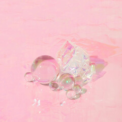 Creative layout with glass balls with iridescent foil ball on pastel pink foil background. 80s, 90s...