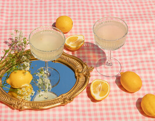 Summer creative layout with vintage mirror with sky reflection, lemons and glasses on pink plaid...
