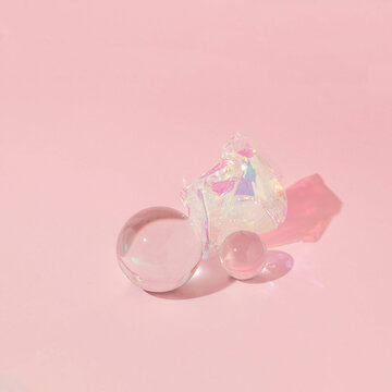 Creative layout with glass balls with iridescent foil ball on pastel pink background. 80s, 90s retro romantic aesthetic love concept. Minimal fashion cosmetic idea.