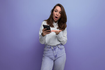 young brown-haired woman chatting on the internet using a mobile phone on a studio background with copy space