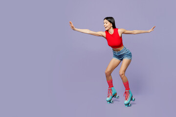 Full body side view fun young latin woman she wear red casual clothes rollers rollerblading with outstretched hands isolated on plain pastel purple background. Summer sport lifestyle leisure concept.