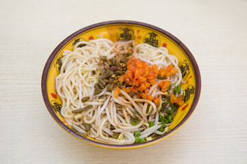 a bowl of hot dry noodles with sesame paste on table