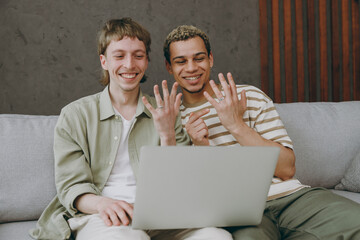 Young happy couple two gay men wear casual clothes use laptop pc tells parents about marriage...