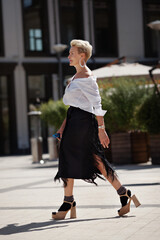 Confidence and sophistication mature woman walks city streets in fashionable ensemble chic white...