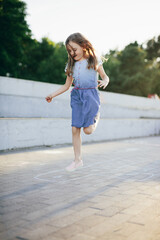 Young girl jumping playing hopscotch in urban neighborhood