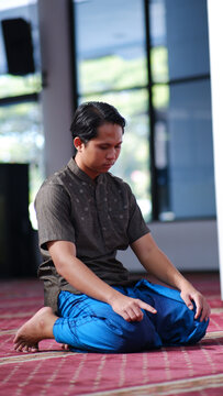 a muslim asian man is sitting tasyahud to perform the prayer