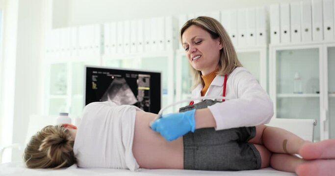 Medical examination of baby girl using ultrasound equipment. Ultrasound operator moves sensor on side of child back examination of kidneys in children