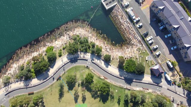 Aerial drone pullback reverse top down view of Barangaroo Reserve along Barangaroo waterfront precinct in Sydney City, NSW Australia on a sunny morning in May 2023     