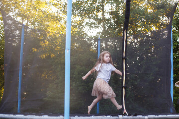 Little child girl jumping on the trampoline in the back yard