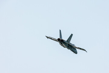 Rear view of a hornet F-18 jet fighter in an Air show festival flying at sub-sonic speed in a clear...