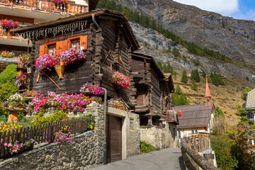 Traditional wooden alpine chalet with geranium flowers on the window in summer, Zermatt alpine...