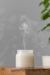 White interior candle in glass with smoke from the wick. Handmade candle. Hugge