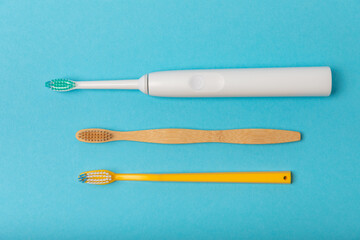 Electric and manual toothbrushes on a blue background. View from above. Oral hygiene. Ordinary toothbrush, eco and electric toothbrush. Oral hygiene. Oral Care Kit. Dentist concept. Dental care. 